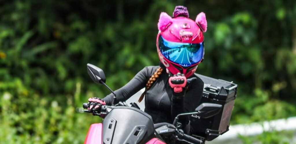 Mujer en scooter con casco con orejas de gato rosas